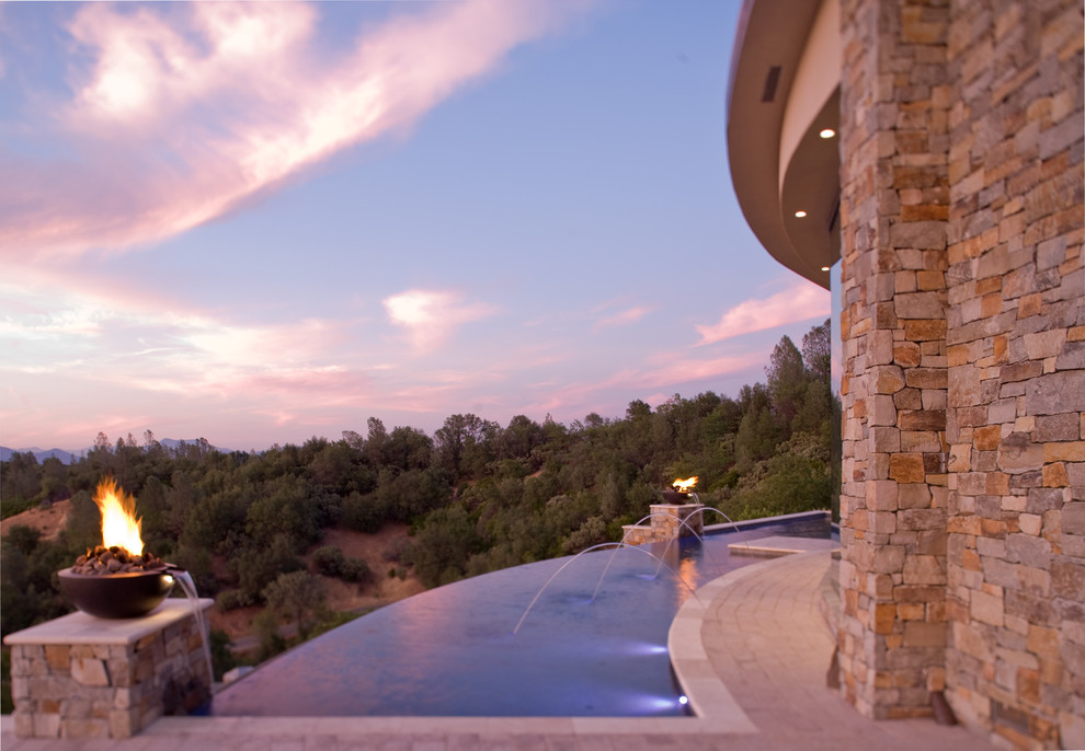 Foto di un'ampia piscina a sfioro infinito contemporanea personalizzata dietro casa con fontane e pavimentazioni in cemento