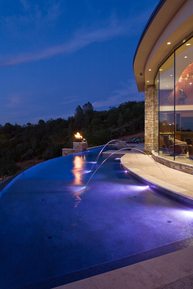 Ejemplo de piscina con fuente infinita contemporánea extra grande a medida en patio trasero con adoquines de hormigón