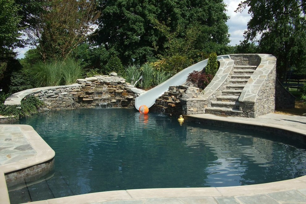 Bild på en mellanstor rustik anpassad pool på baksidan av huset, med marksten i betong och vattenrutschkana