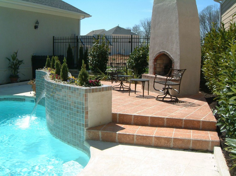 Modelo de piscina natural tradicional de tamaño medio tipo riñón en patio trasero con adoquines de hormigón