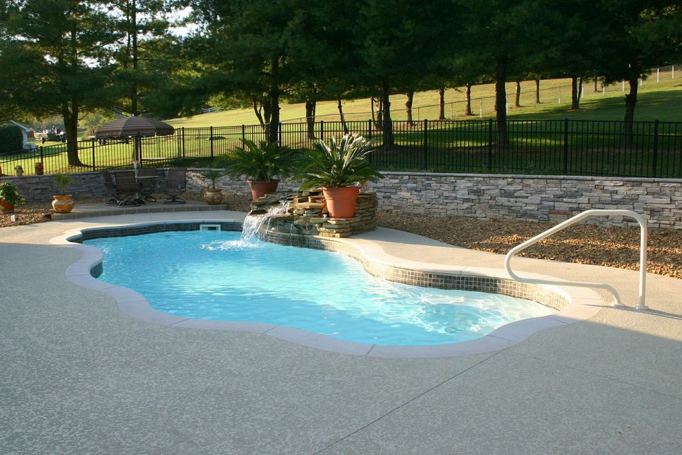 Diseño de piscina natural clásica pequeña a medida en patio trasero con adoquines de hormigón