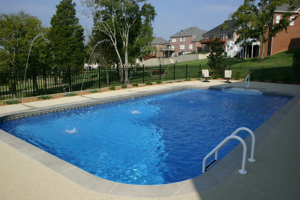 Foto de piscina clásica grande rectangular en patio trasero con adoquines de hormigón