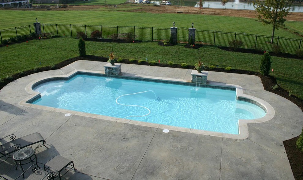 Foto de piscina natural tradicional de tamaño medio rectangular en patio trasero con adoquines de hormigón