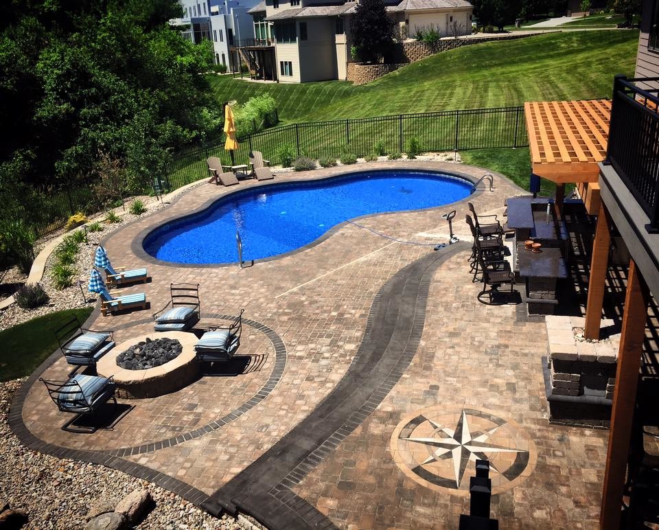 Ejemplo de piscina clásica grande tipo riñón en patio trasero con adoquines de hormigón