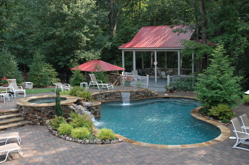 Traditional custom shaped swimming pool in Atlanta with brick paving.