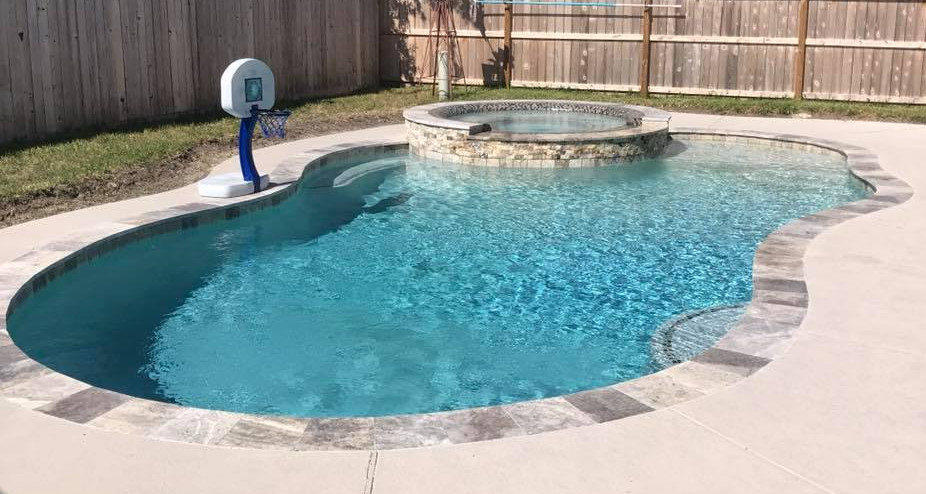 Modelo de piscina natural de estilo americano de tamaño medio a medida en patio trasero con losas de hormigón