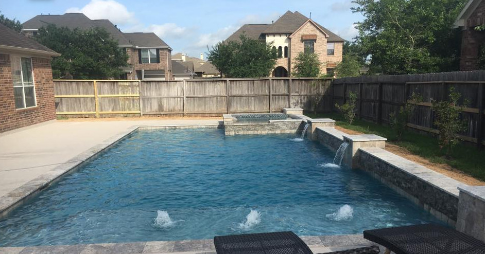 Mittelgroßer Moderner Schwimmteich hinter dem Haus in rechteckiger Form mit Wasserspiel und Betonplatten in Houston