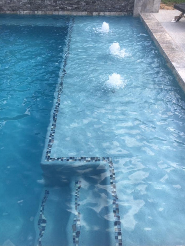Mittelgroßer Moderner Schwimmteich hinter dem Haus in rechteckiger Form mit Wasserspiel und Betonplatten in Houston