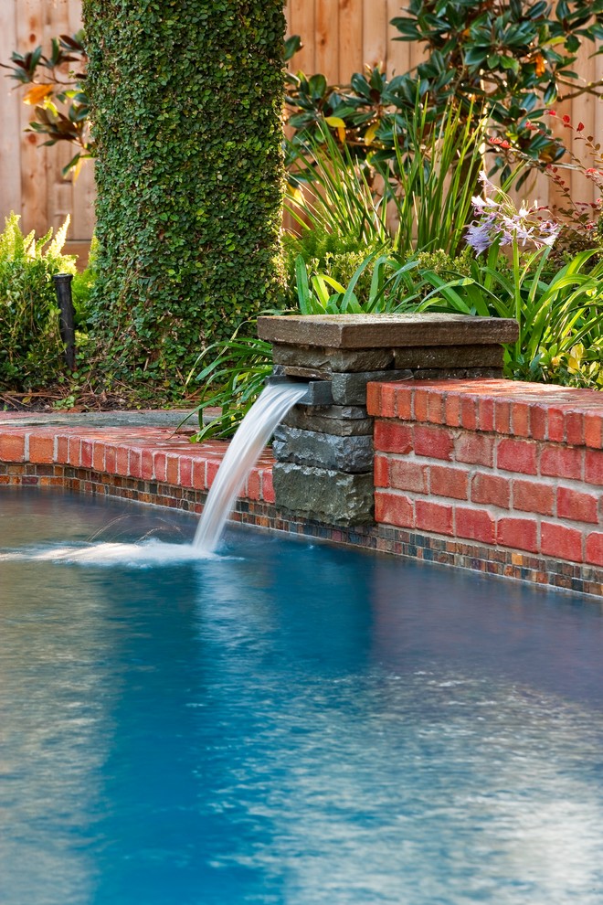 Modelo de piscina con fuente natural clásica de tamaño medio a medida en patio trasero con adoquines de ladrillo