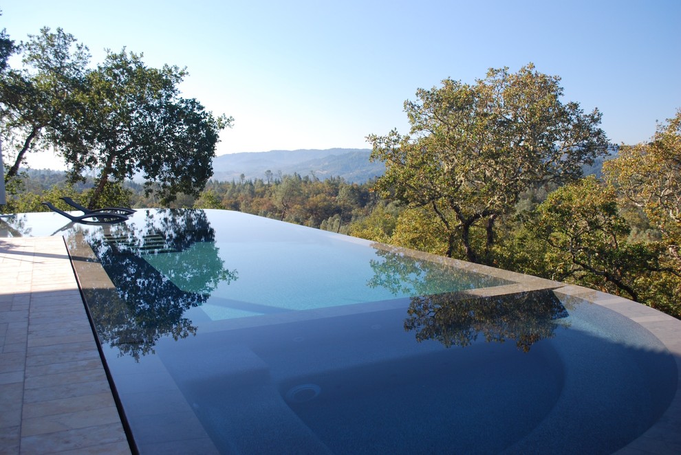 Esempio di una grande piscina a sfioro infinito minimal personalizzata dietro casa con piastrelle