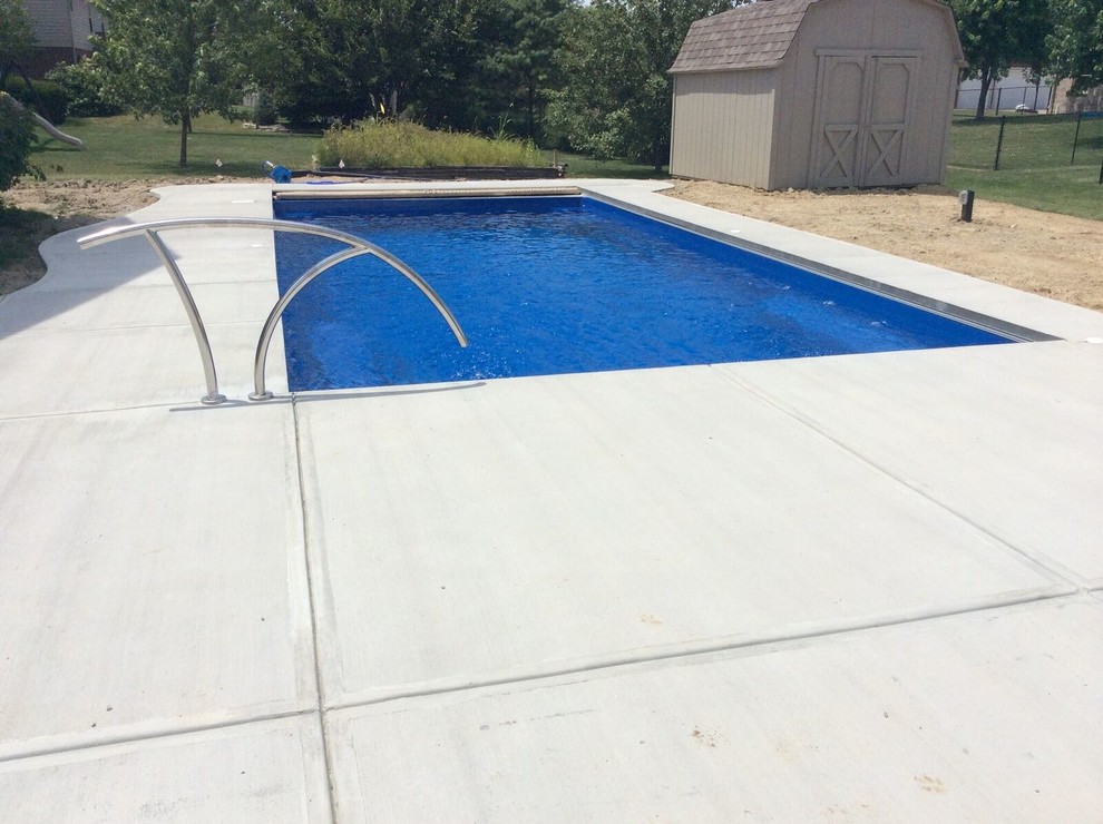 На фото: спортивный, прямоугольный бассейн среднего размера на заднем дворе в стиле неоклассика (современная классика) с покрытием из бетонных плит