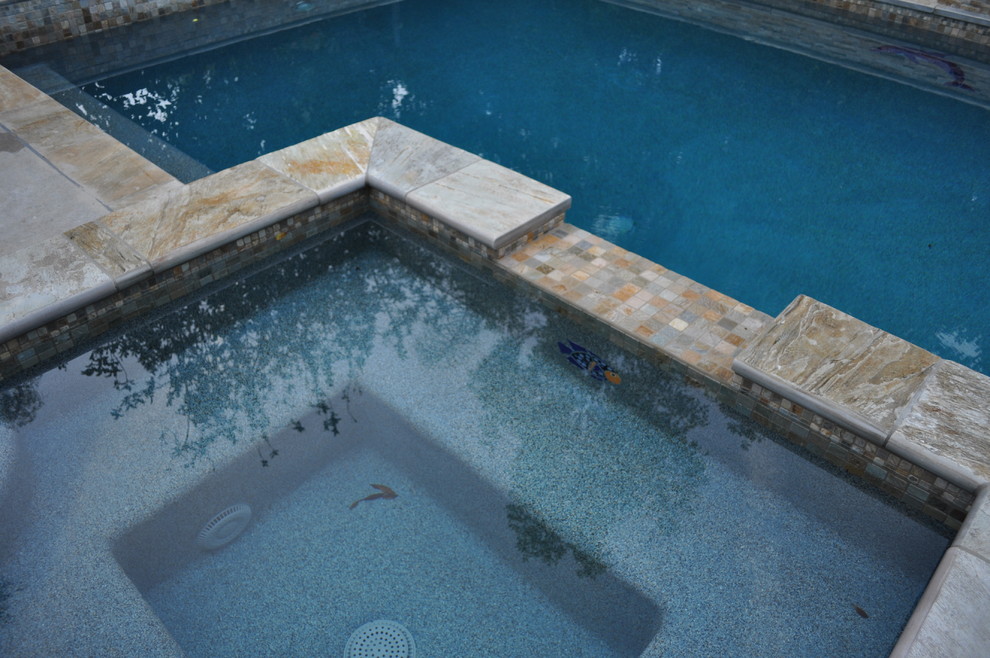 Ispirazione per una grande piscina minimal rettangolare dietro casa con una vasca idromassaggio e lastre di cemento