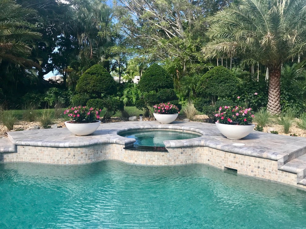 This is an example of a large mediterranean back kidney-shaped swimming pool in Miami with natural stone paving.