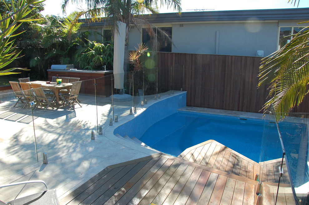 Exempel på en modern njurformad pool på baksidan av huset, med trädäck