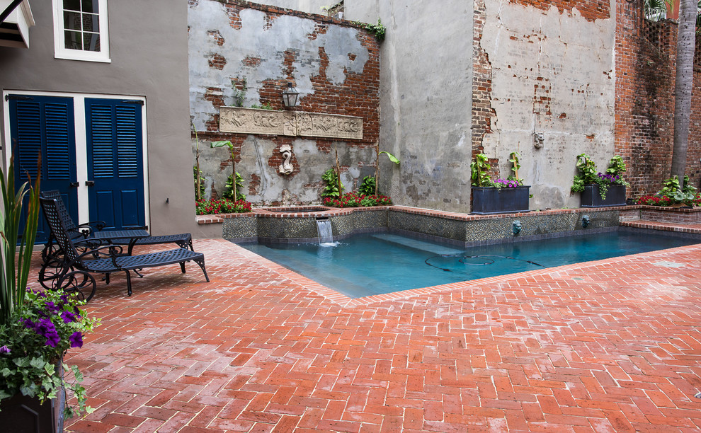 Modelo de piscinas y jacuzzis mediterráneos de tamaño medio en forma de L en patio trasero con adoquines de ladrillo