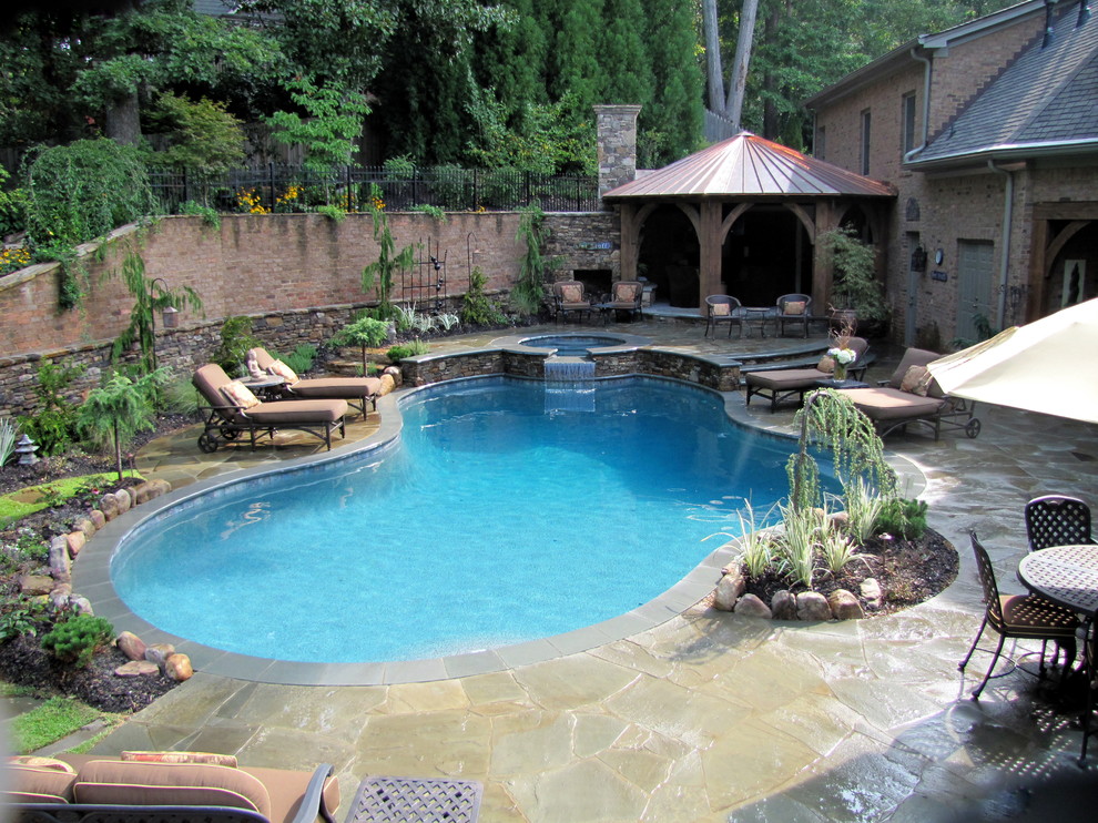 Diseño de piscinas y jacuzzis tradicionales de tamaño medio a medida en patio trasero con adoquines de piedra natural