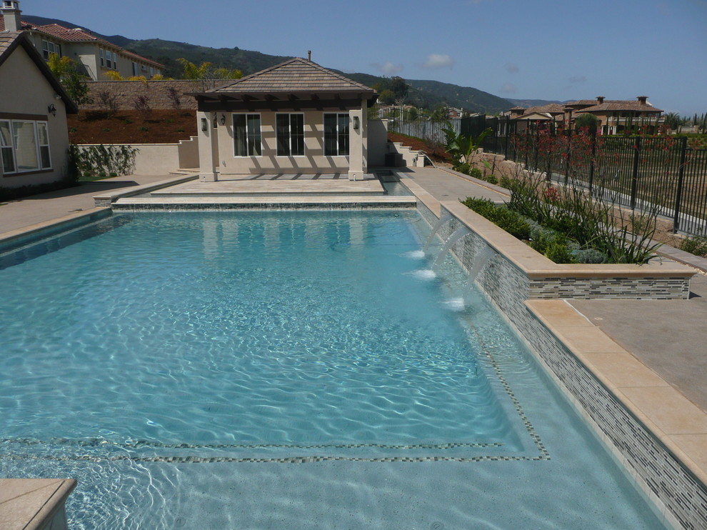 На фото: огромный спортивный, прямоугольный бассейн на заднем дворе в современном стиле с покрытием из бетонных плит и джакузи с