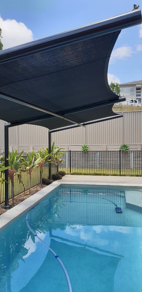 Foto de piscina natural moderna de tamaño medio rectangular en patio trasero con entablado