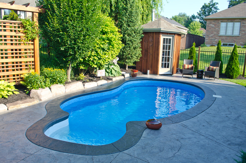Photo of a medium sized traditional back custom shaped swimming pool in Toronto with a pool house and concrete slabs.