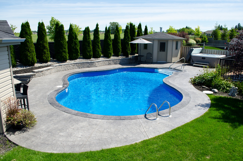 Cette image montre une piscine arrière traditionnelle de taille moyenne et sur mesure avec une dalle de béton.