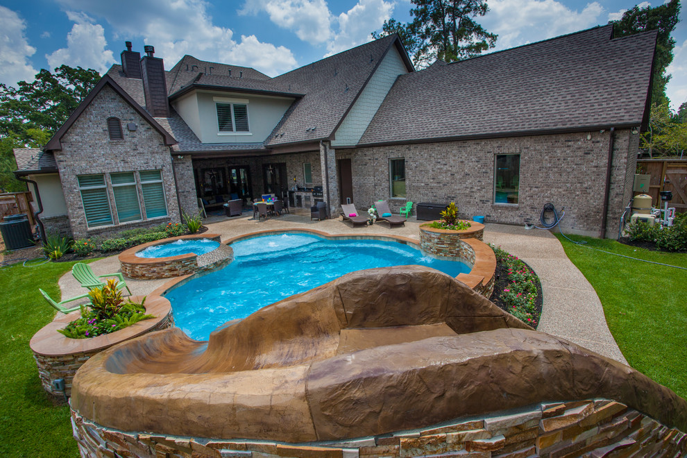 На фото: естественный бассейн среднего размера, произвольной формы на заднем дворе в стиле модернизм с водной горкой и настилом с