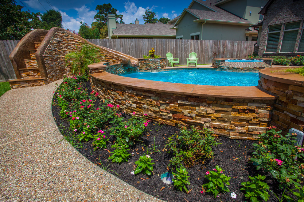 Medium sized modern back custom shaped natural swimming pool in Houston with a water slide and decking.