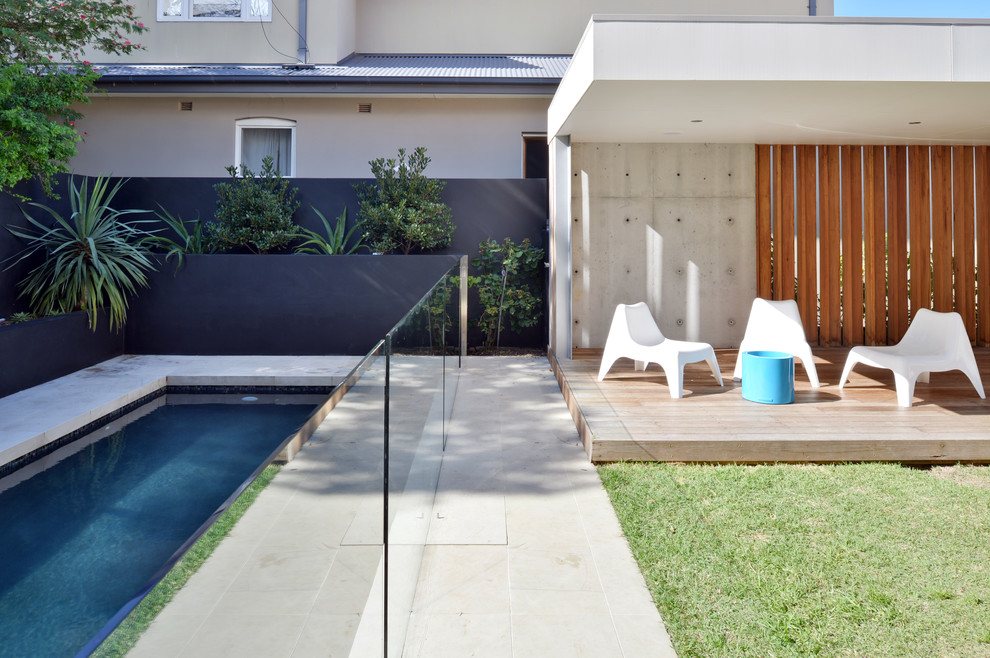 This is an example of a contemporary back rectangular swimming pool in Sydney with stamped concrete.