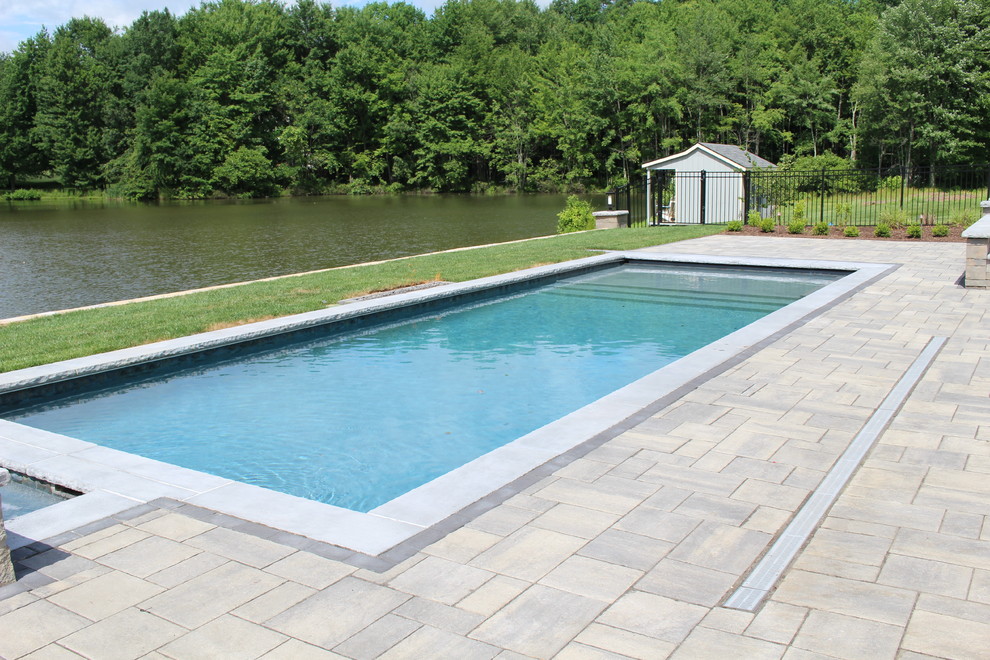 Modelo de piscinas y jacuzzis alargados minimalistas de tamaño medio rectangulares en patio trasero con adoquines de hormigón