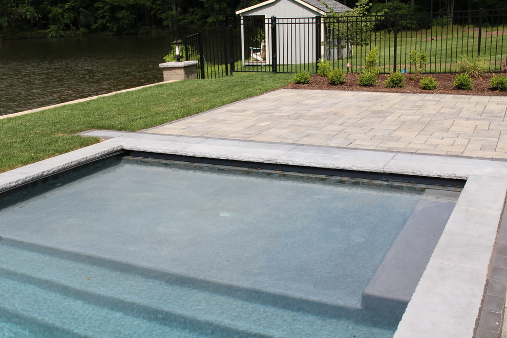 Esempio di una piscina monocorsia moderna rettangolare di medie dimensioni e dietro casa con una vasca idromassaggio e pavimentazioni in cemento
