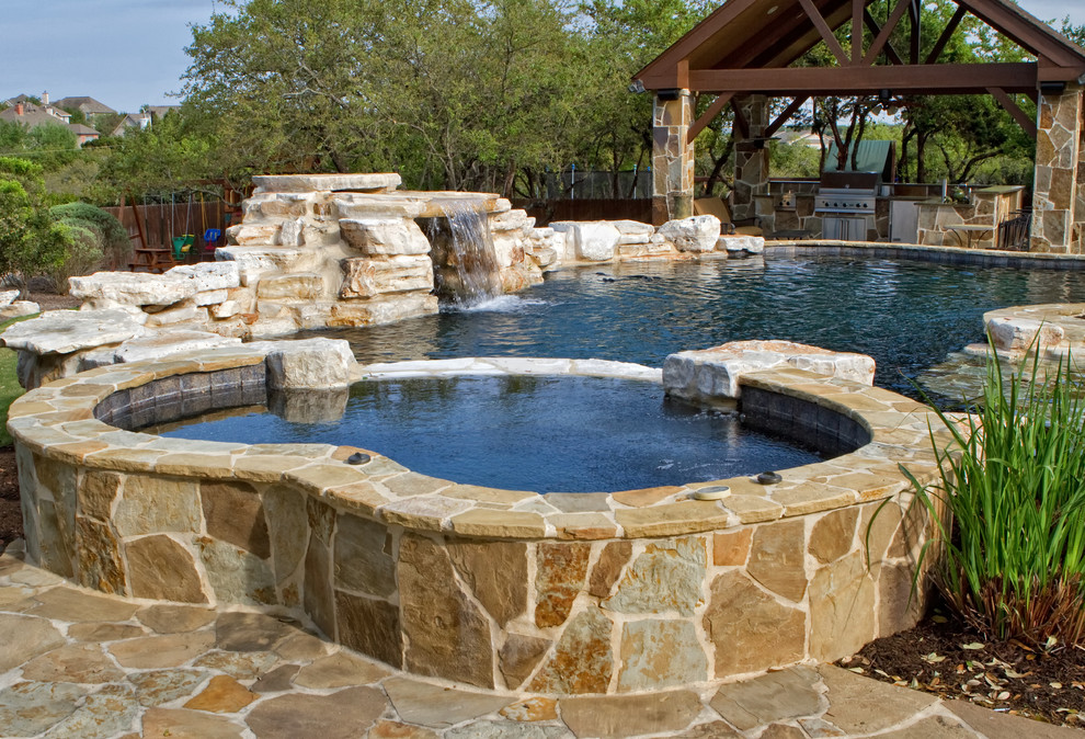 Idee per una piscina naturale chic personalizzata di medie dimensioni e dietro casa con pavimentazioni in pietra naturale e una vasca idromassaggio