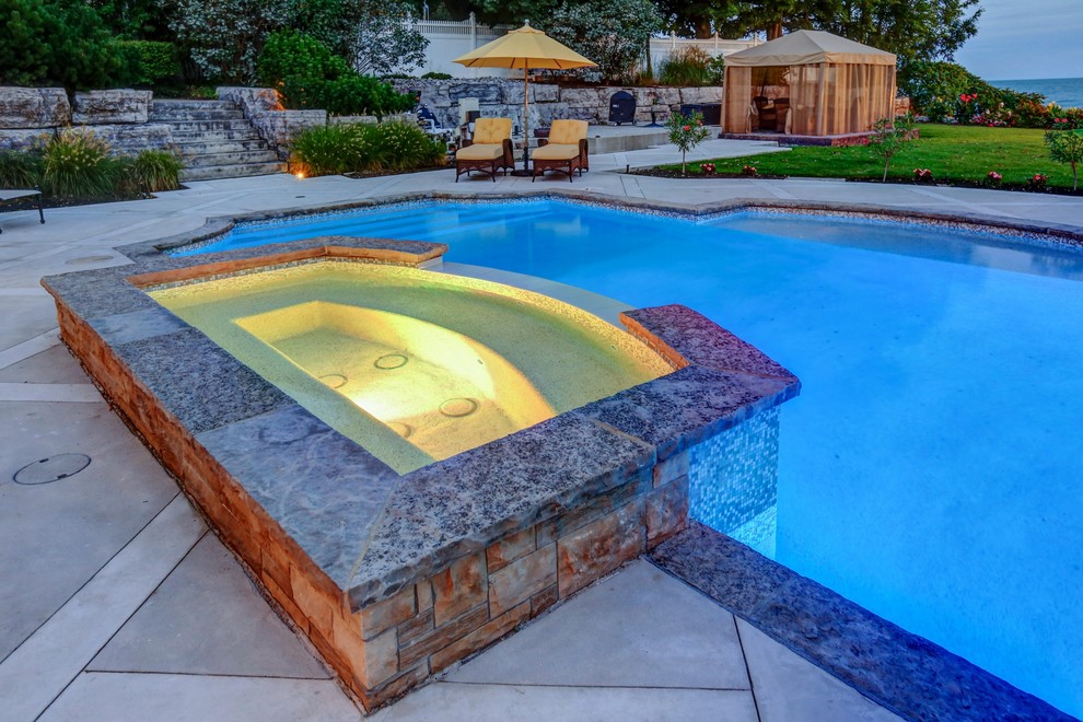 Esempio di una piscina chic rettangolare di medie dimensioni e dietro casa con una vasca idromassaggio e cemento stampato
