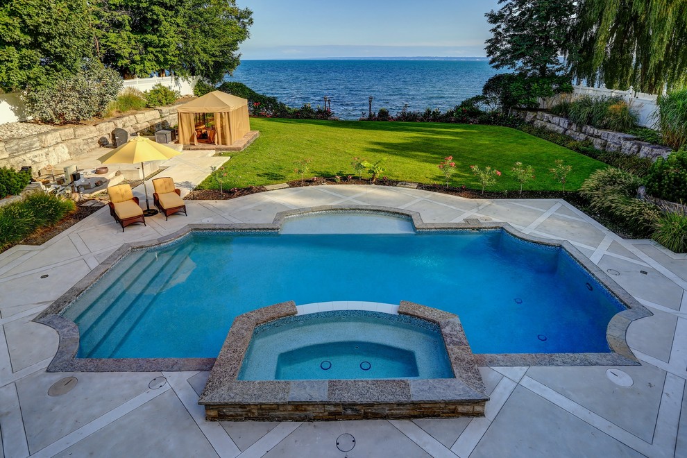 Foto di una piscina classica rettangolare di medie dimensioni e dietro casa con una vasca idromassaggio e cemento stampato