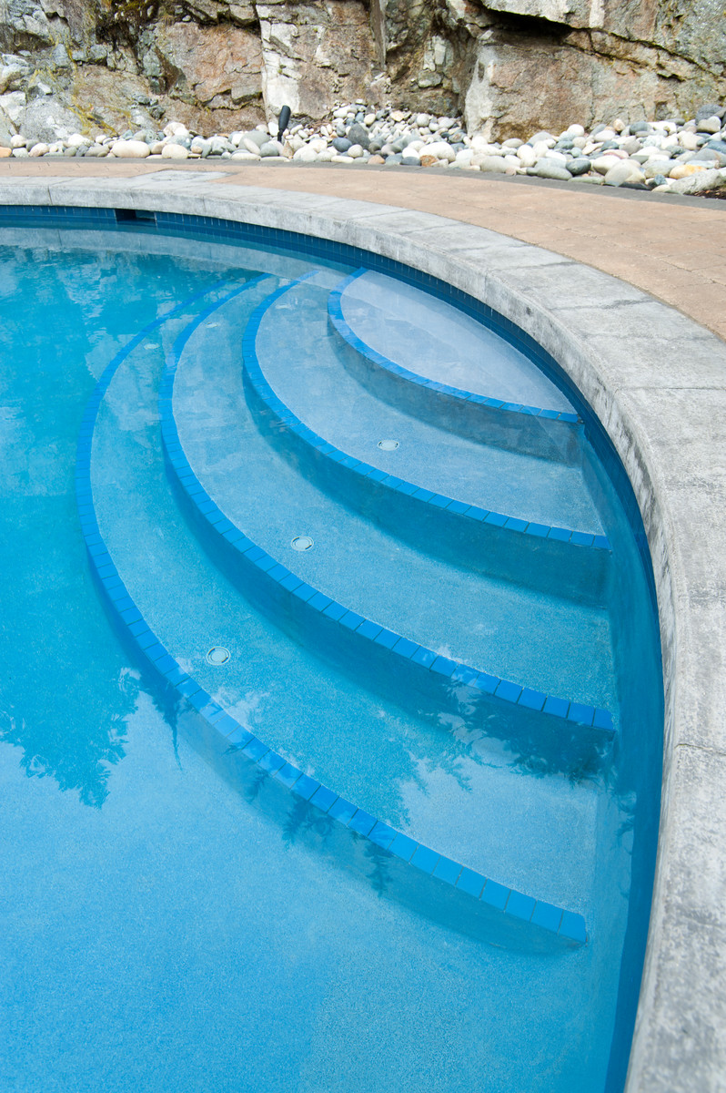 Ejemplo de piscina bohemia a medida en patio trasero con adoquines de ladrillo