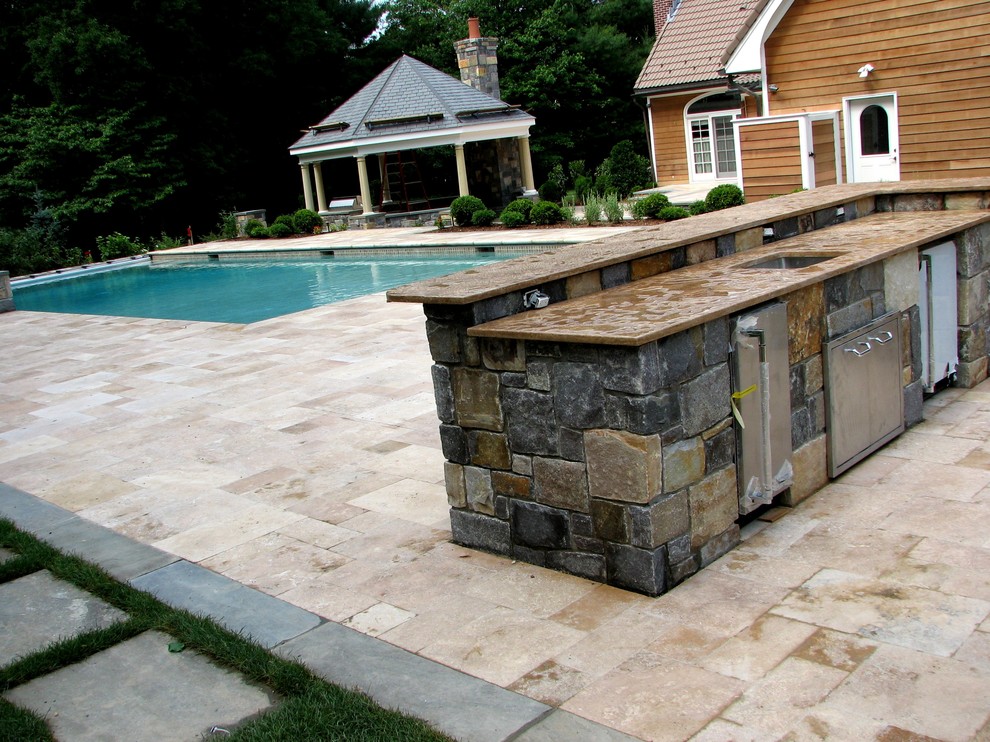 Example of a large classic backyard stone and custom-shaped lap pool design in New York