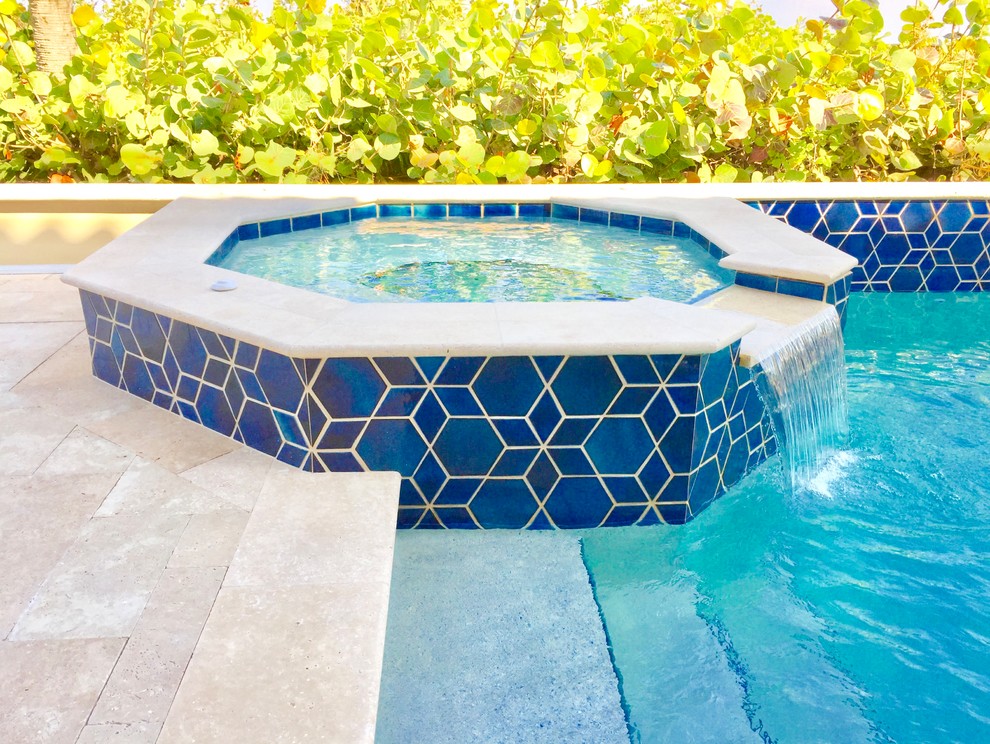 Immagine di una piscina monocorsia stile marino rettangolare di medie dimensioni e dietro casa con una vasca idromassaggio e pavimentazioni in pietra naturale