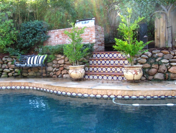 Inspiration for a large mediterranean back custom shaped lengths swimming pool in Sacramento with a water feature and natural stone paving.