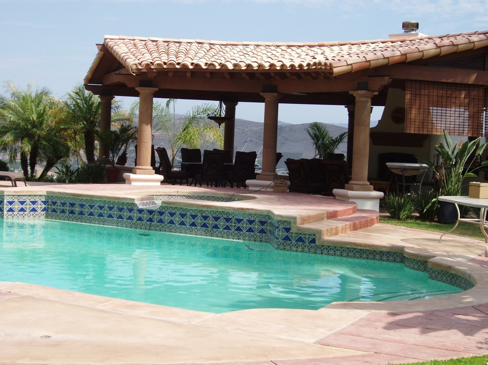 Ejemplo de piscinas y jacuzzis alargados mediterráneos grandes a medida en patio trasero con adoquines de piedra natural