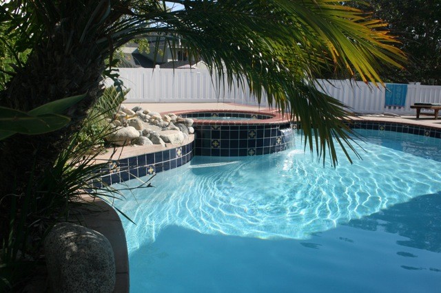Foto di una grande piscina monocorsia mediterranea personalizzata dietro casa con una vasca idromassaggio e pavimentazioni in pietra naturale
