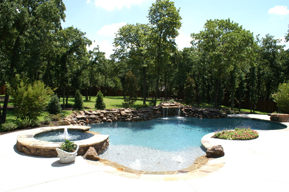Modelo de piscina con fuente natural tradicional extra grande a medida en patio trasero con losas de hormigón