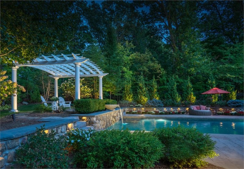 Ejemplo de piscina clásica de tamaño medio rectangular en patio trasero con suelo de hormigón estampado