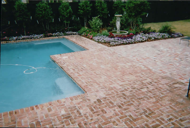 Ejemplo de piscina con fuente tradicional de tamaño medio en patio trasero con adoquines de ladrillo