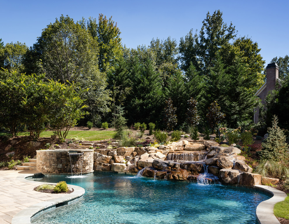 Foto de piscina natural tradicional grande a medida en patio trasero con adoquines de piedra natural