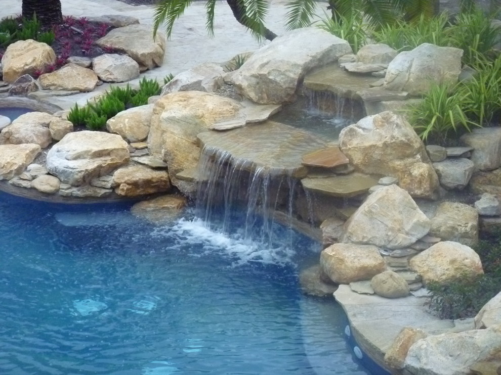 Foto de piscina con fuente alargada clásica de tamaño medio a medida en patio trasero con adoquines de piedra natural