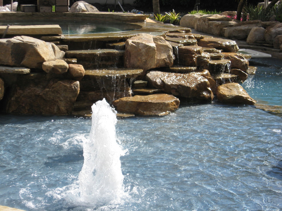 Diseño de piscina con fuente contemporánea grande a medida en patio trasero con adoquines de piedra natural