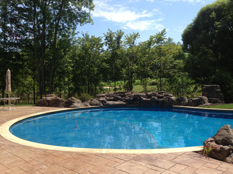 Idee per una grande piscina naturale stile rurale personalizzata dietro casa con una vasca idromassaggio e pavimentazioni in cemento