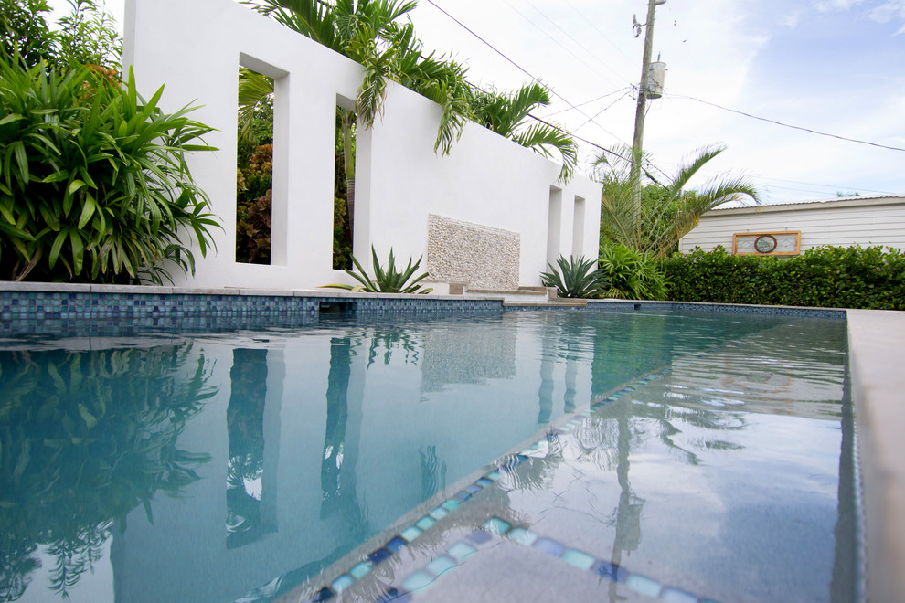 Ispirazione per una piscina tropicale rettangolare di medie dimensioni e dietro casa con fontane e pedane