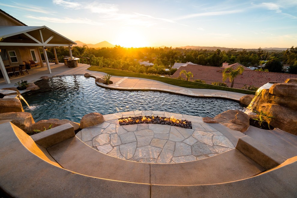 Inspiration for a large contemporary back custom shaped lengths swimming pool in San Diego with a water slide and concrete paving.