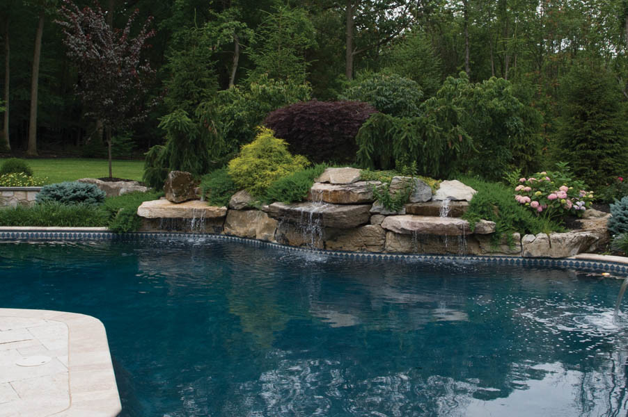 Exemple d'une très grande piscine naturelle et arrière chic sur mesure avec un point d'eau et une terrasse en bois.