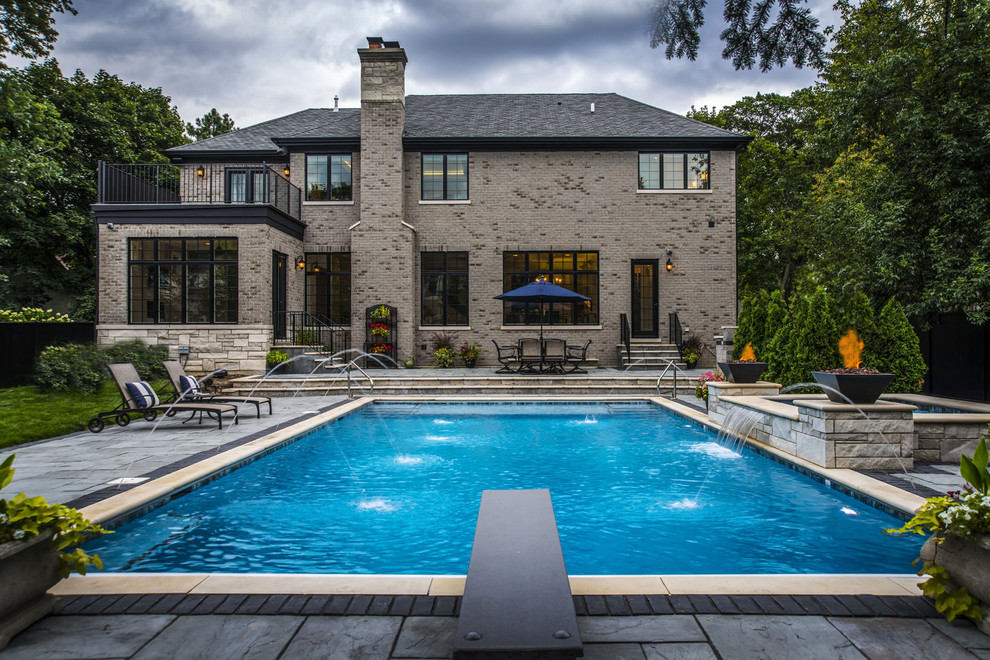 Foto di una piscina chic rettangolare di medie dimensioni e dietro casa con una vasca idromassaggio e pavimentazioni in pietra naturale