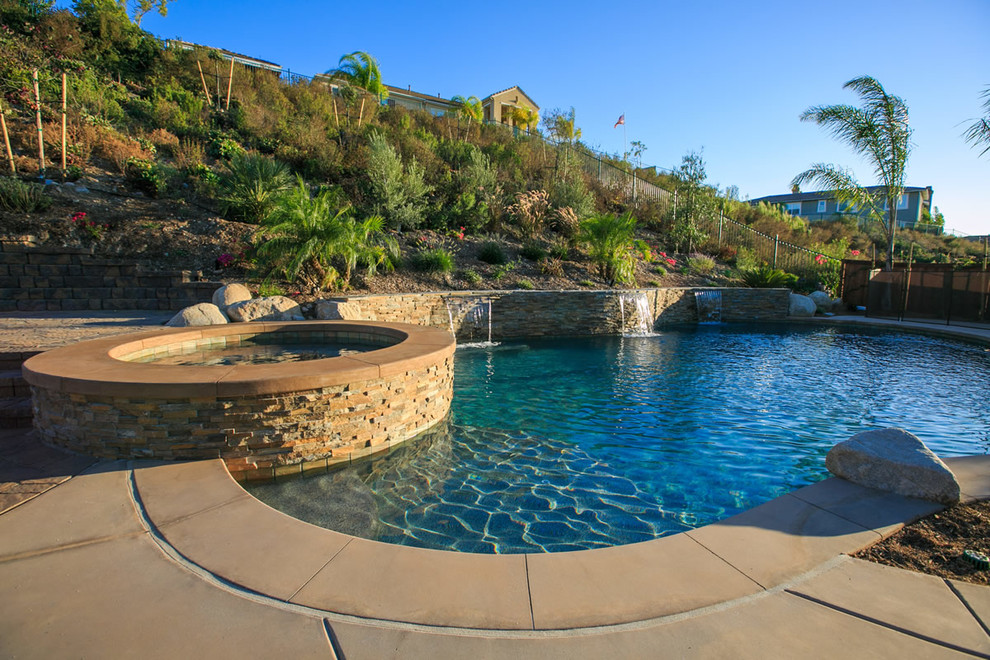 This is an example of an expansive back custom shaped swimming pool in San Diego with a water feature and concrete paving.